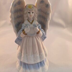 Porcelan angel figurine holding a harp with delicate detailing